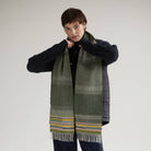 Person wearing a long, patterned scarf with a plain background