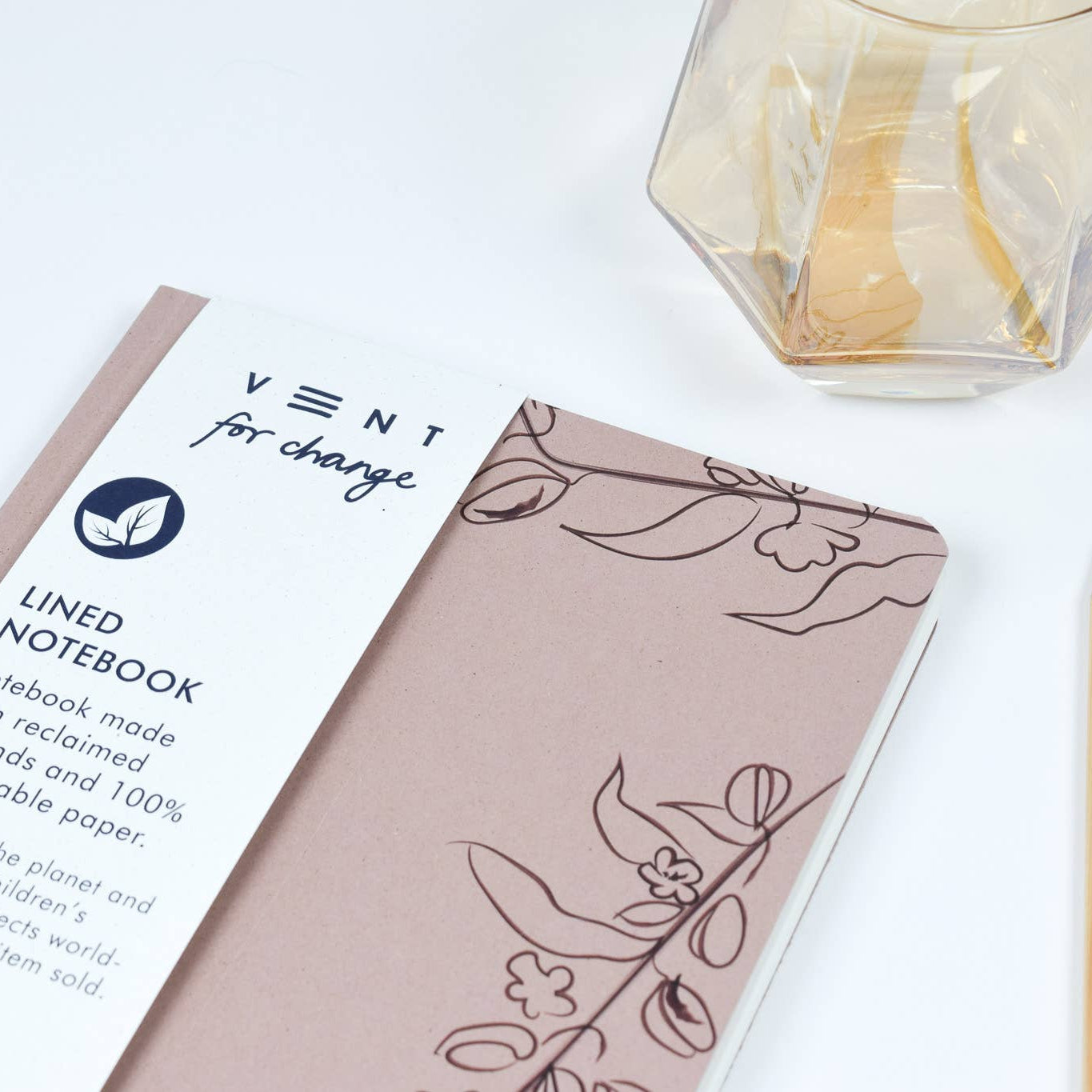 Notebook with 'Vent for Change' label on a white surface with a pencil and candle.