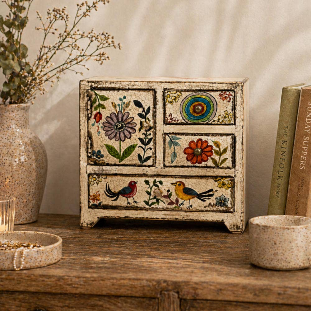 Decorative wooden box with floral and bird patterns on a wooden surface.