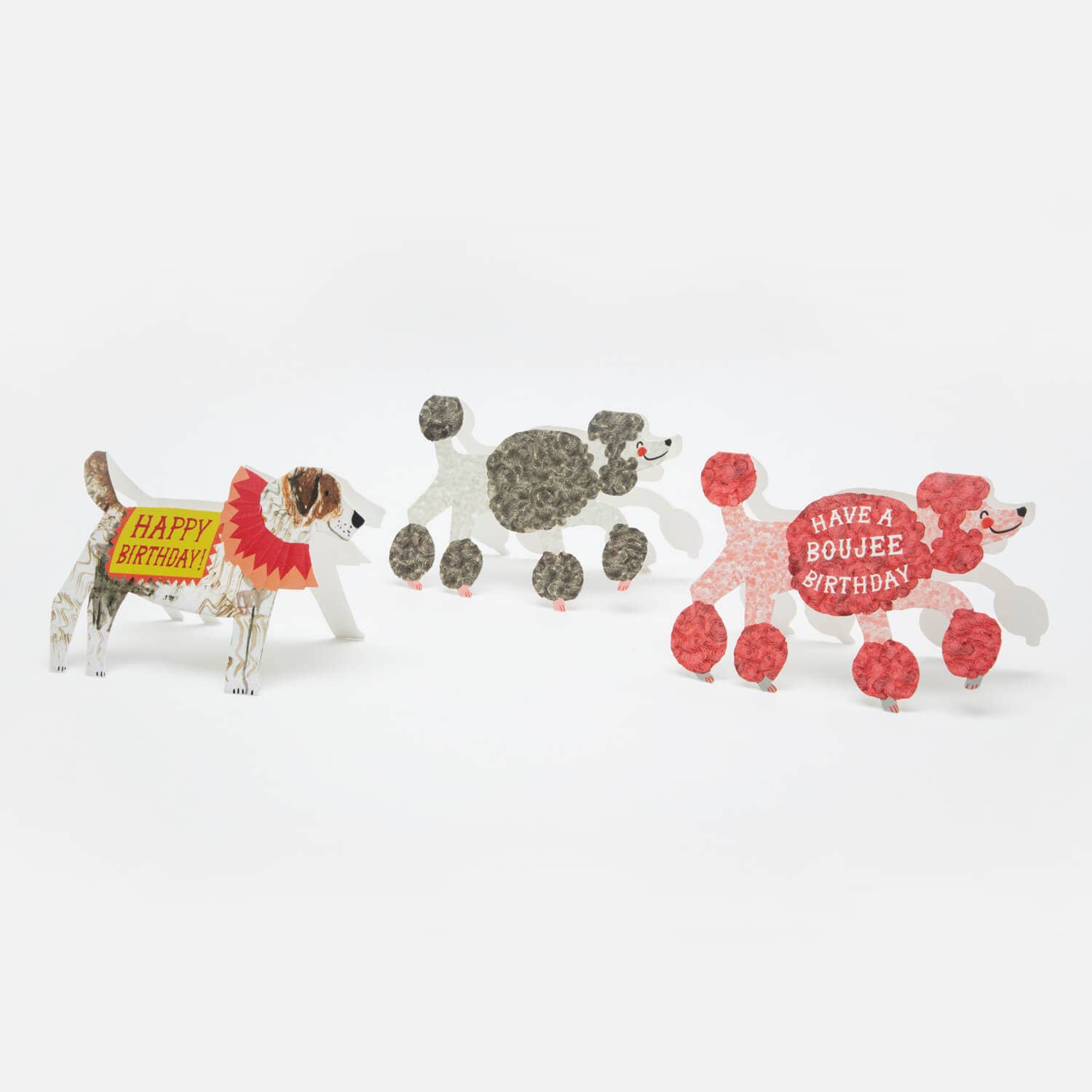 Three paper dog figures with birthday-themed signs on a white background