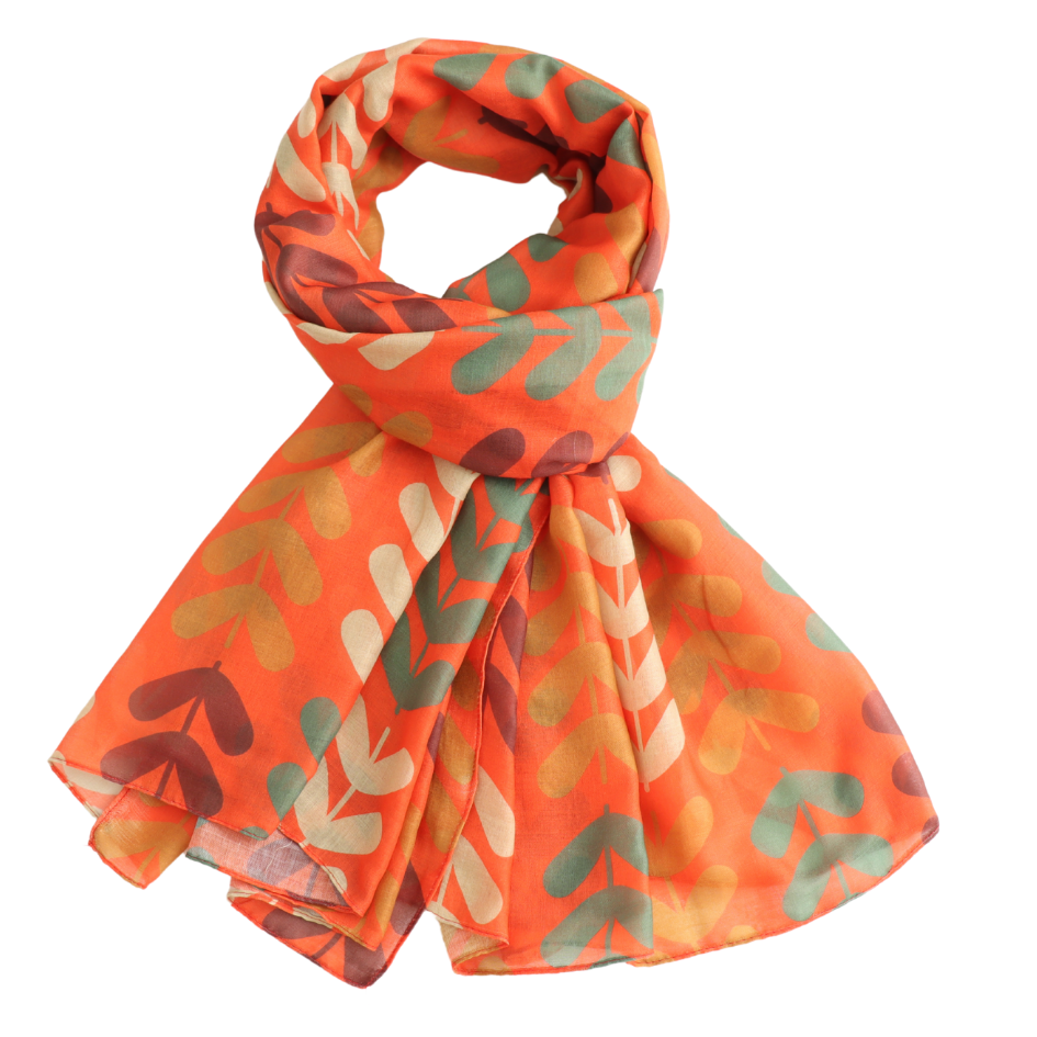 An orange scarf with a pattern of abstract leaf-like shapes in sage green, cream, and dark brown, styled in a loop on a white background.