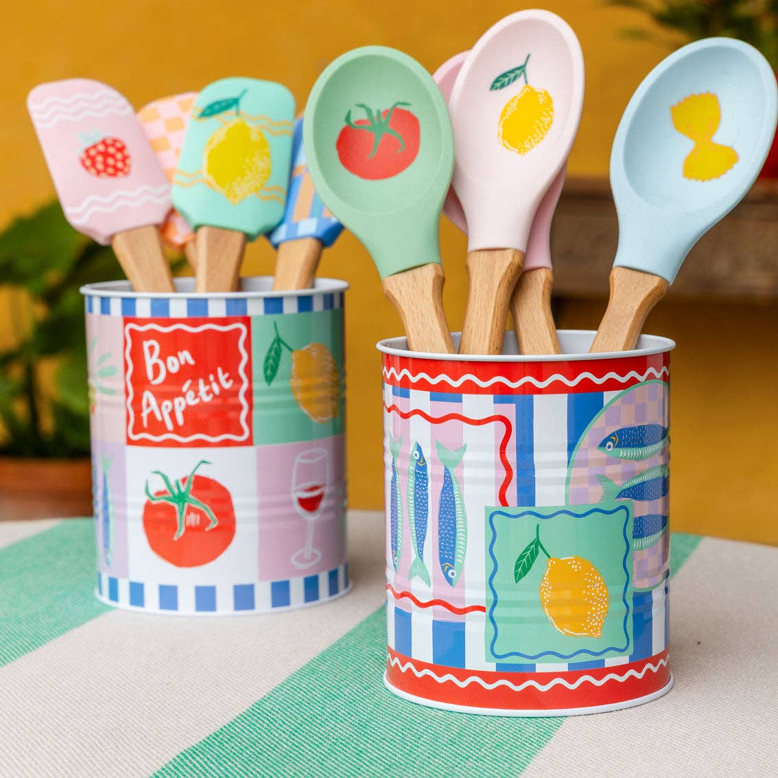 Colorful kitchen utensils in patterned tins on a table with a blurred background
