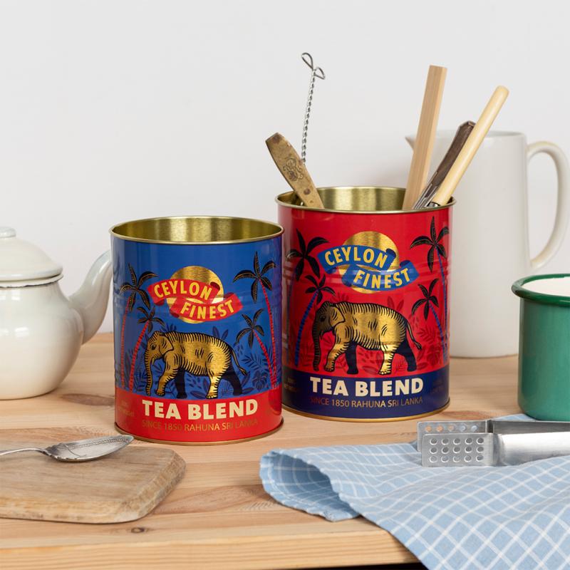 Two tin cans labeled 'Ceylon's Finest Tea Blend' on a wooden surface with kitchen items.