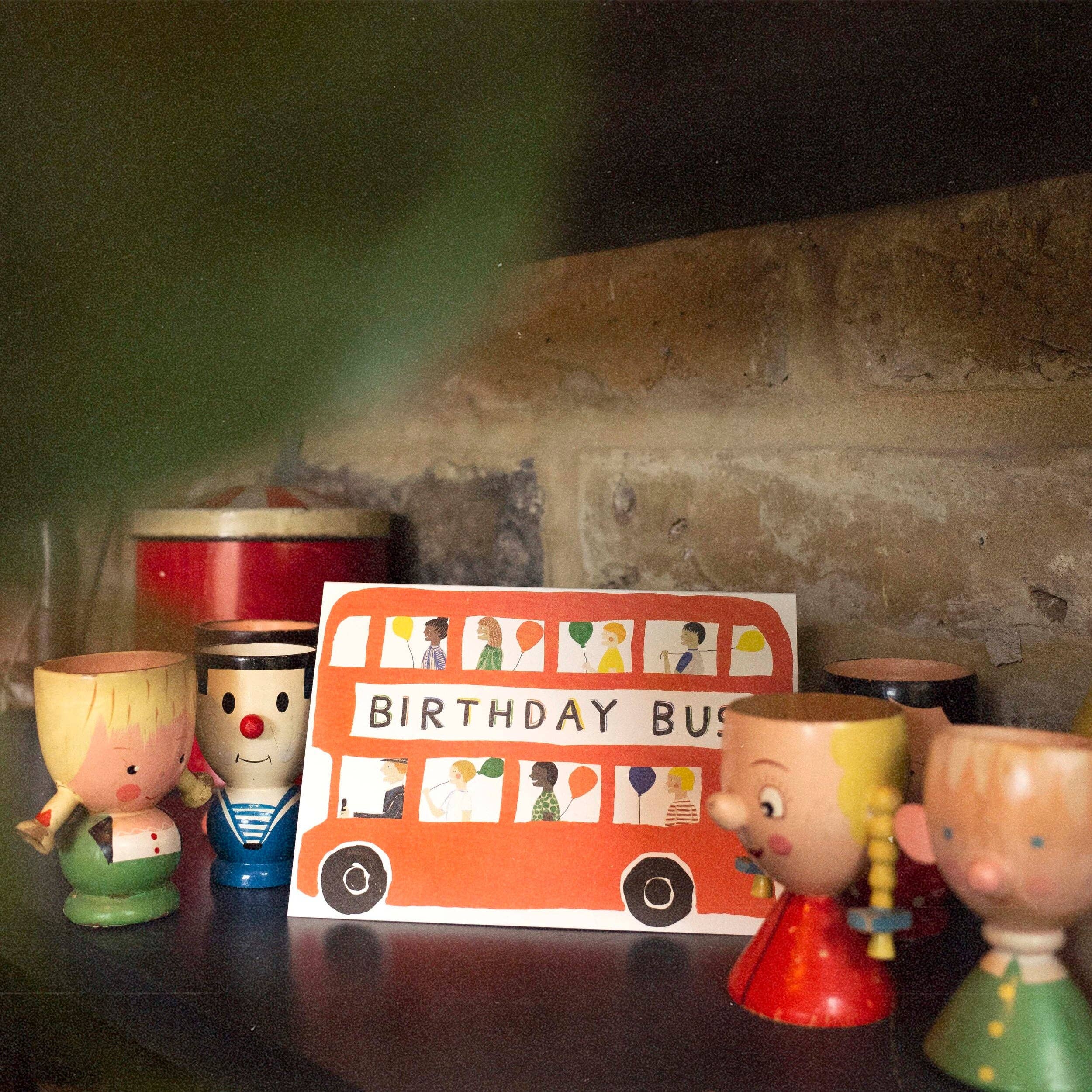 Children's birthday party decorations with a card and small figurines on a dark surface.