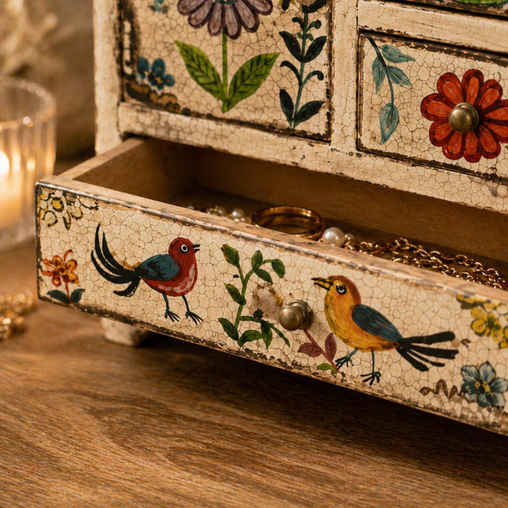 Decorative jewelry box with floral and bird designs on a wooden surface.