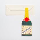 Greeting card designed like a champagne bottle with 'Congratulations' text, attached to an envelope.