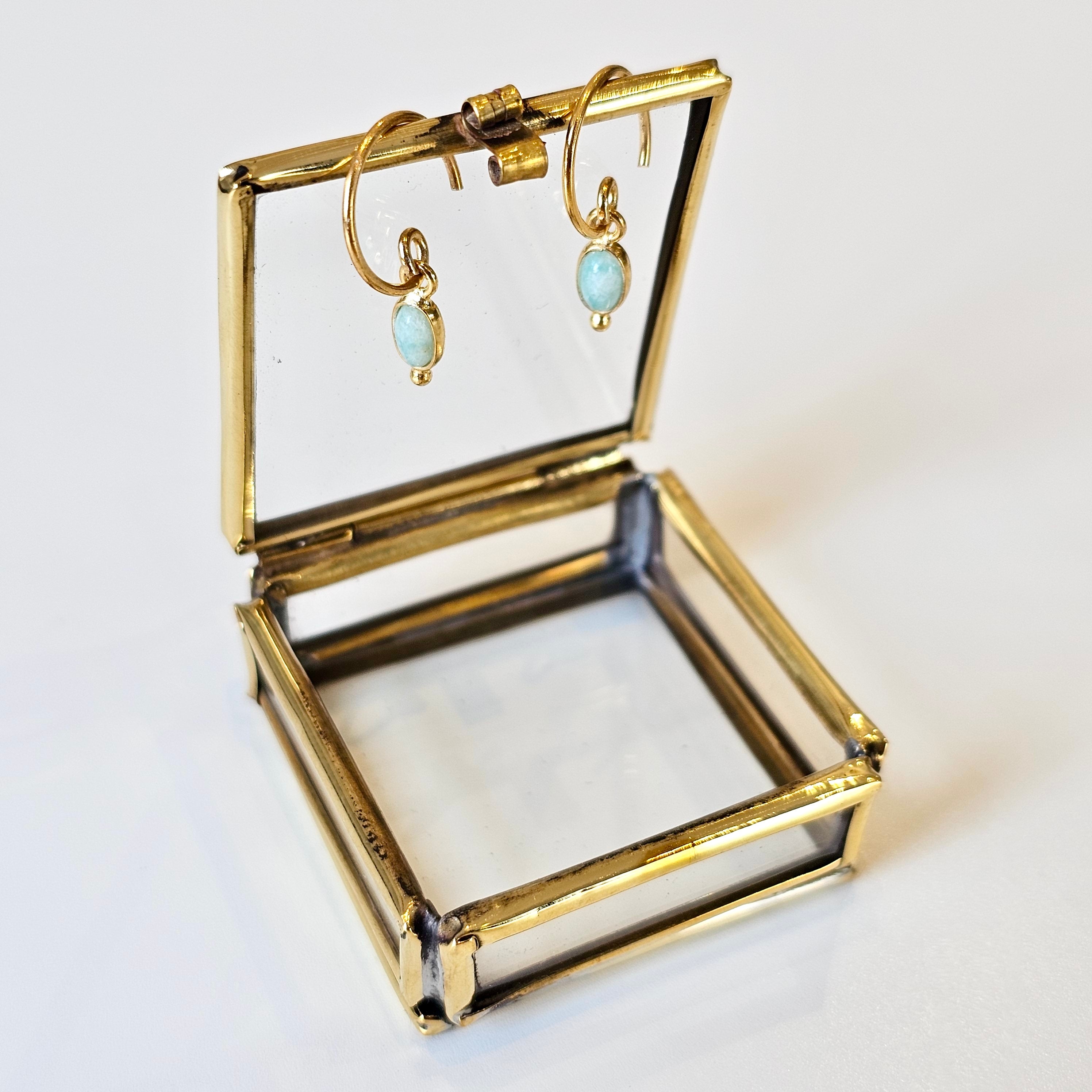 Gold jewelry box with open lid displaying earrings on a white background