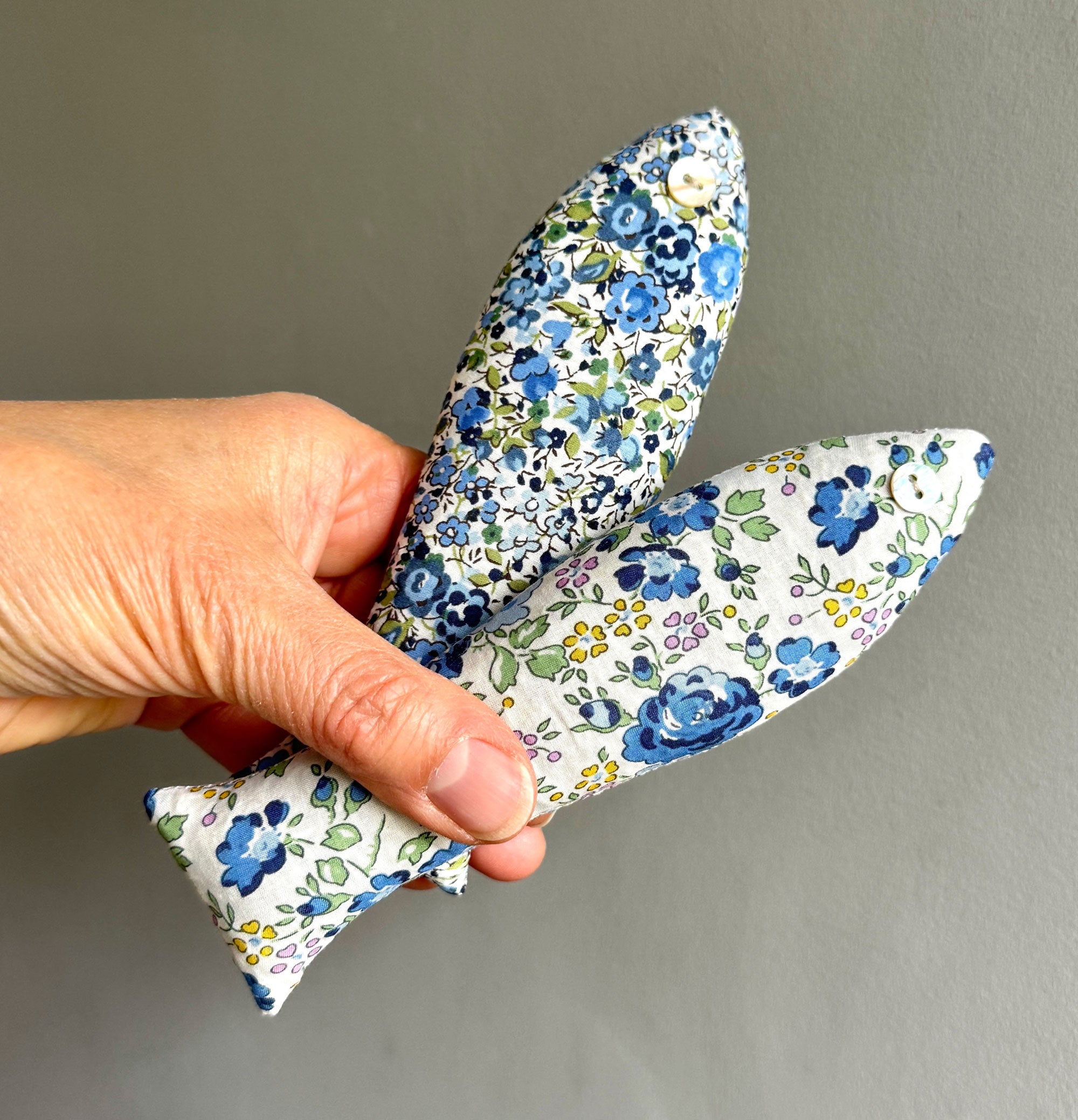 Hand holding a floral-patterned fabric sachet against a plain background