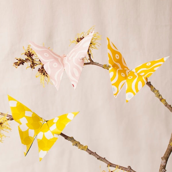 Butterfly-shaped decorations on branches with a neutral background