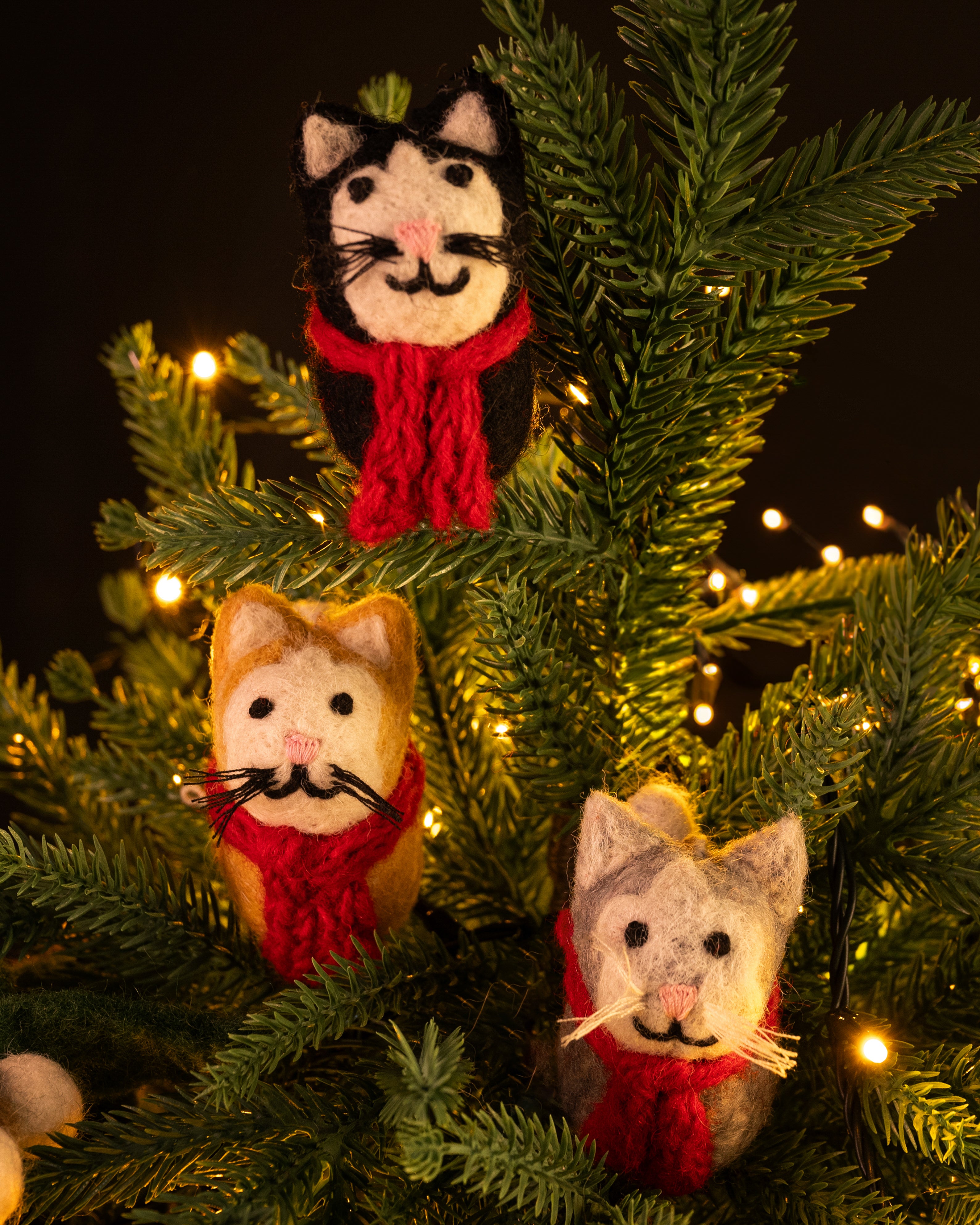 Cat-shaped ornaments with scarves on a decorated Christmas tree.
