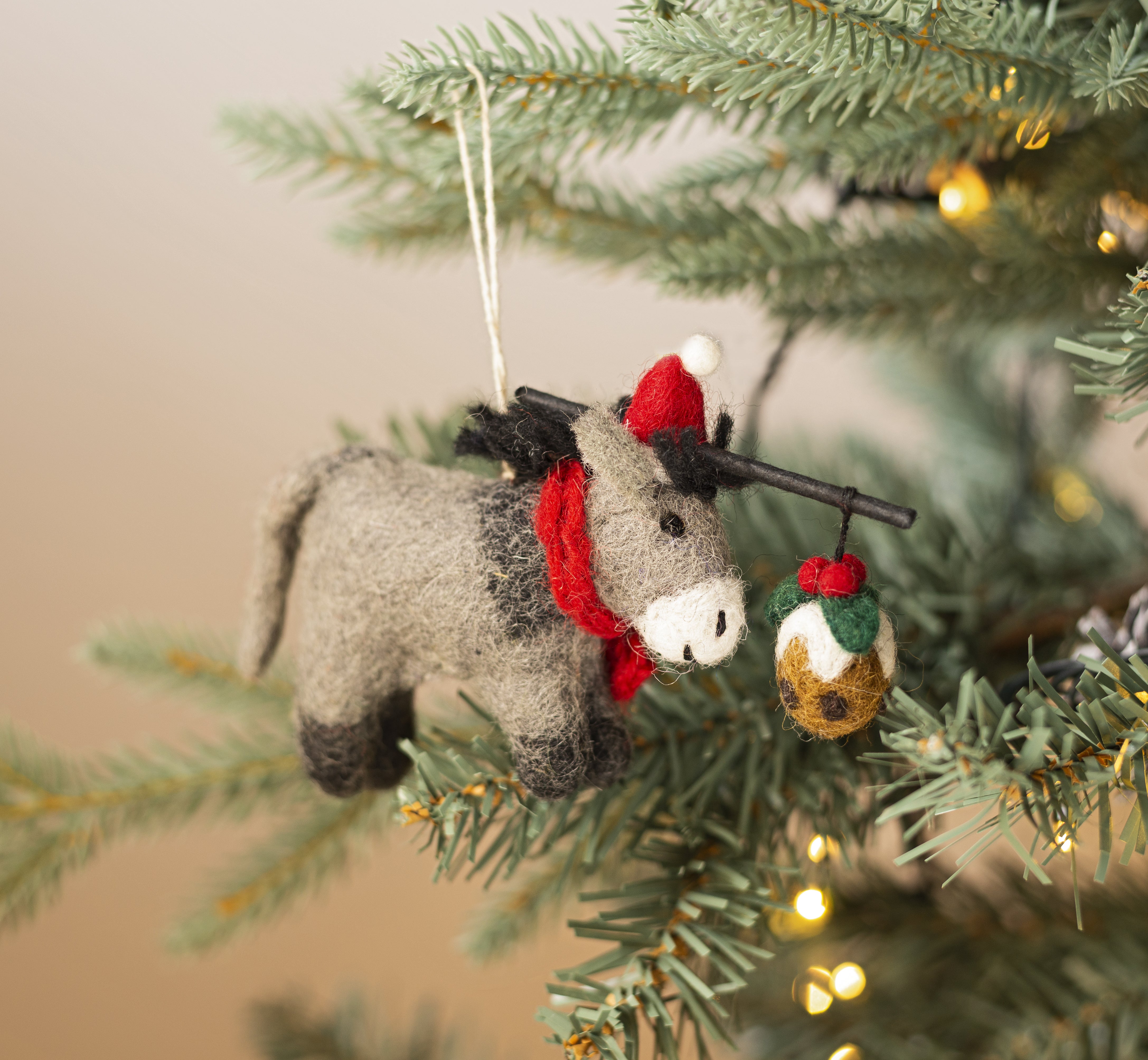 Felted donkey ornament with red scarf hanging on a Christmas tree.