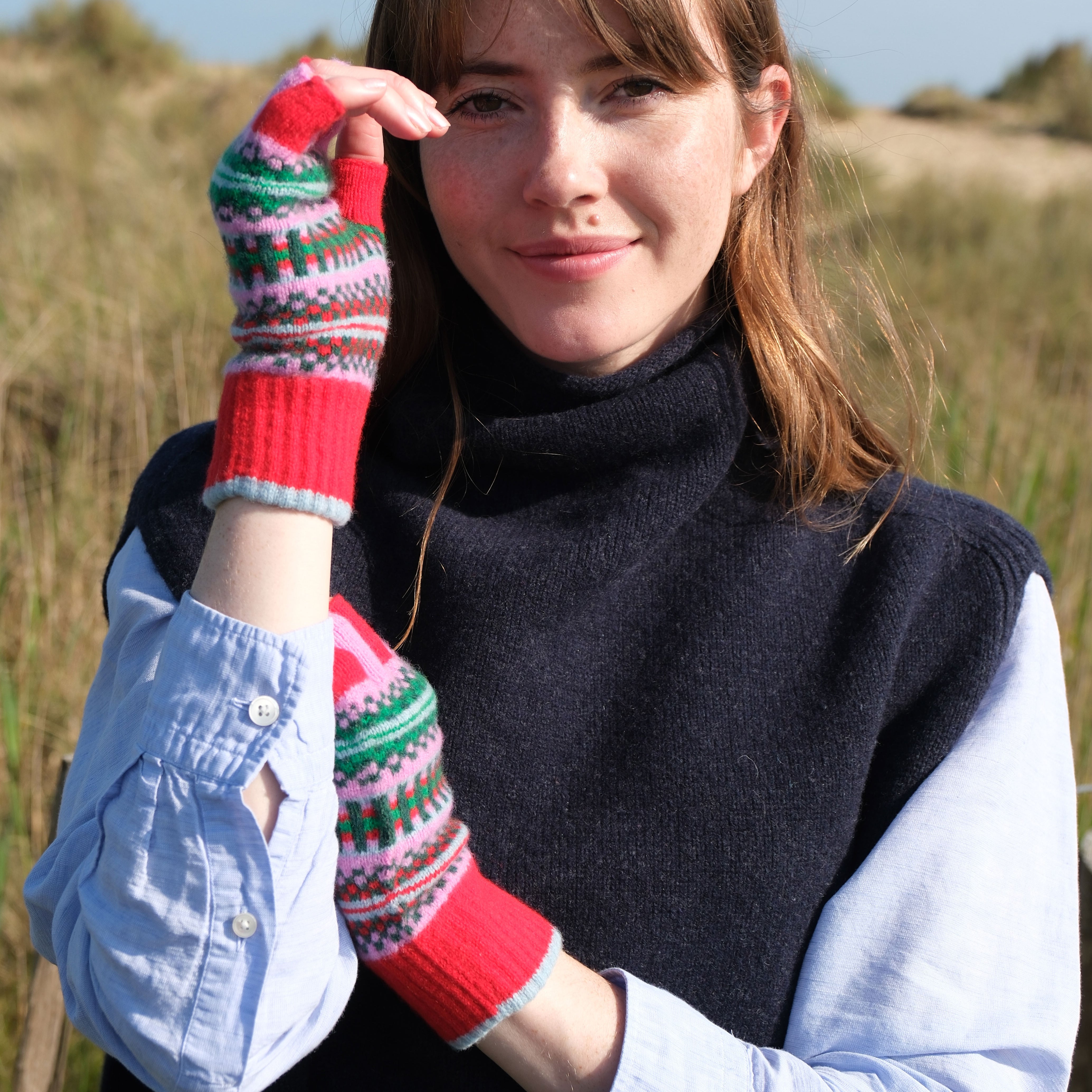 Woman wearing colorful mittens outdoors with a clear sky