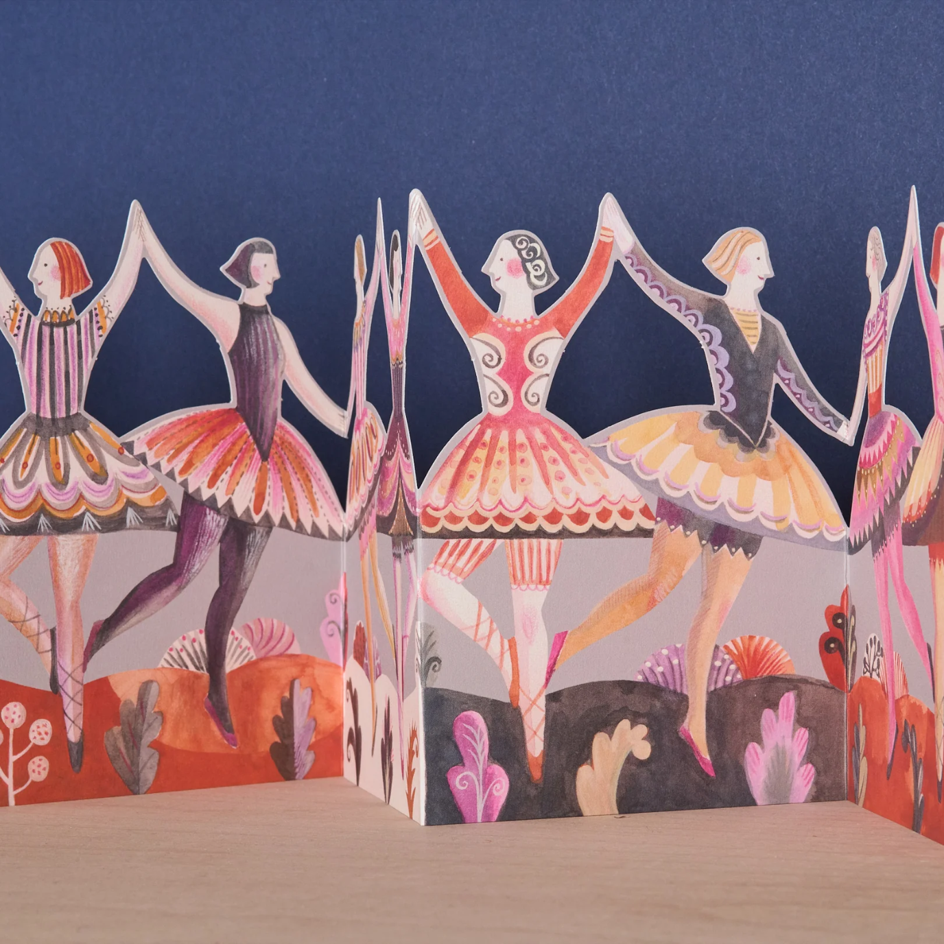 Colourful paper concertina card of dancers against a blue background
