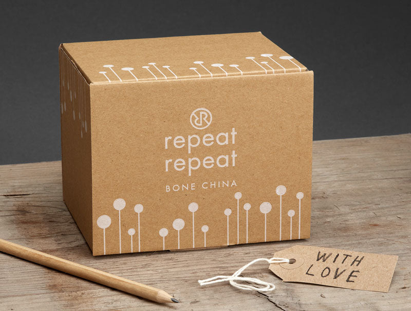 Brown cardboard box with 'repeat repeat' branding on a wooden surface