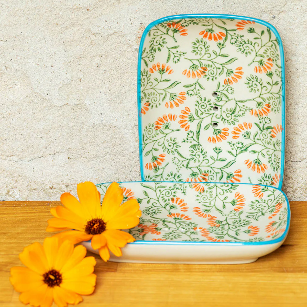 Floral-patterned soap dish on a wooden surface with yellow flowers.