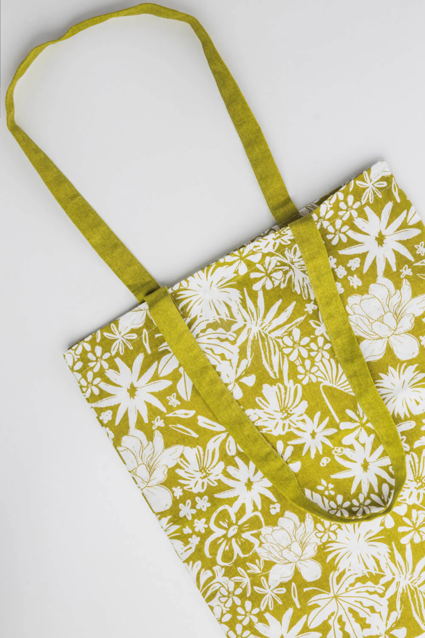 Floral-patterned bag with green strap on a white background