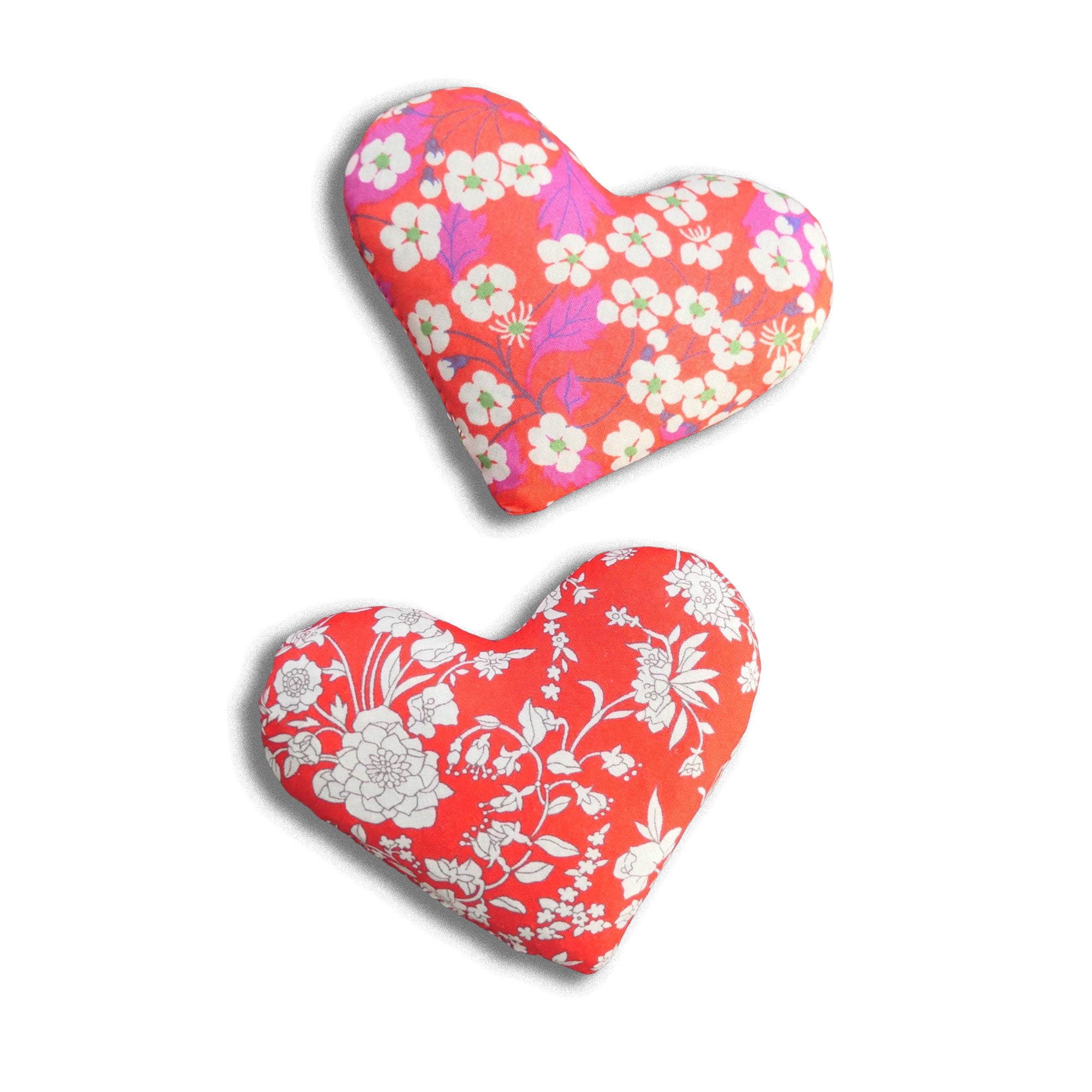 Two heart-shaped cushions with floral patterns on a white background
