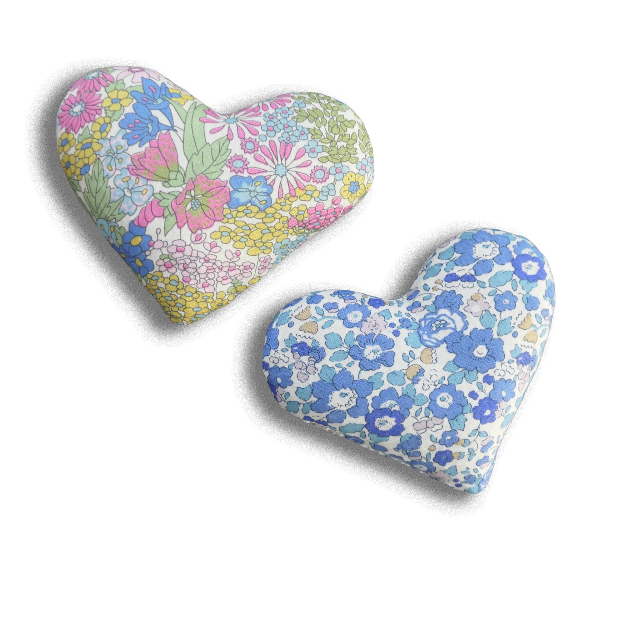 Two pastel heart-shaped lavender sachets with floral patterns on a white background
