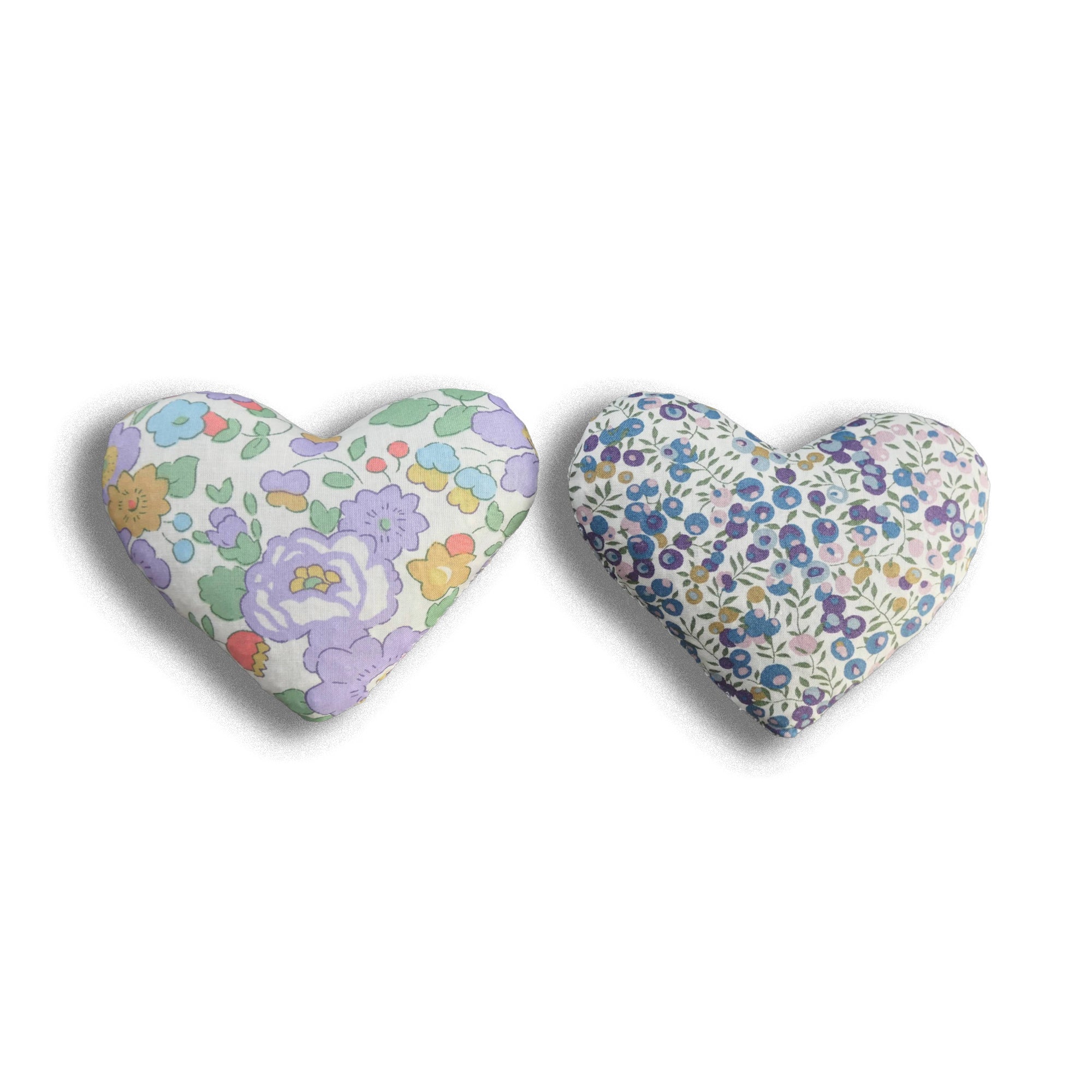Two heart-shaped floral cushions on a white background