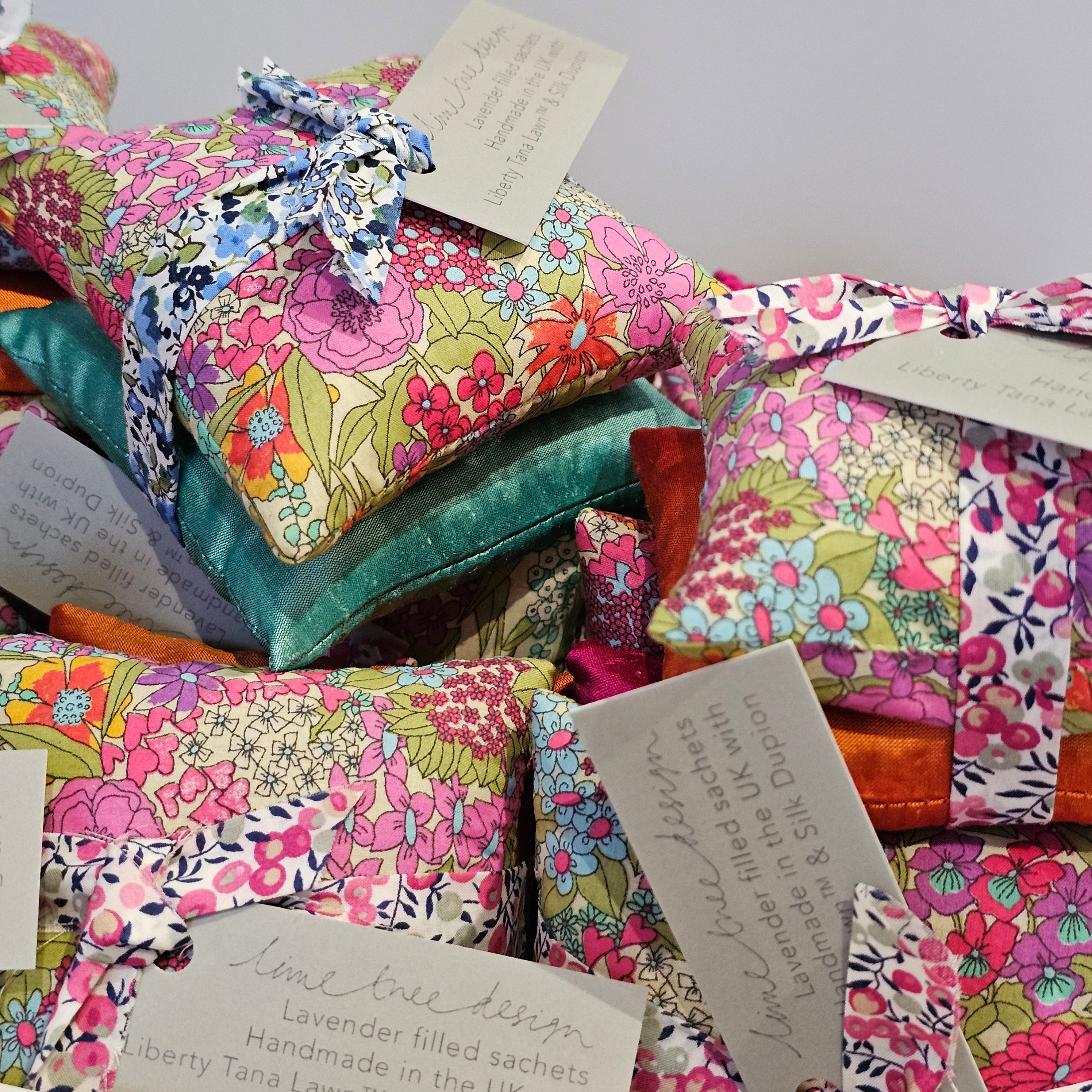 Colourful fabric pouches with floral patterns and cards on a gray background