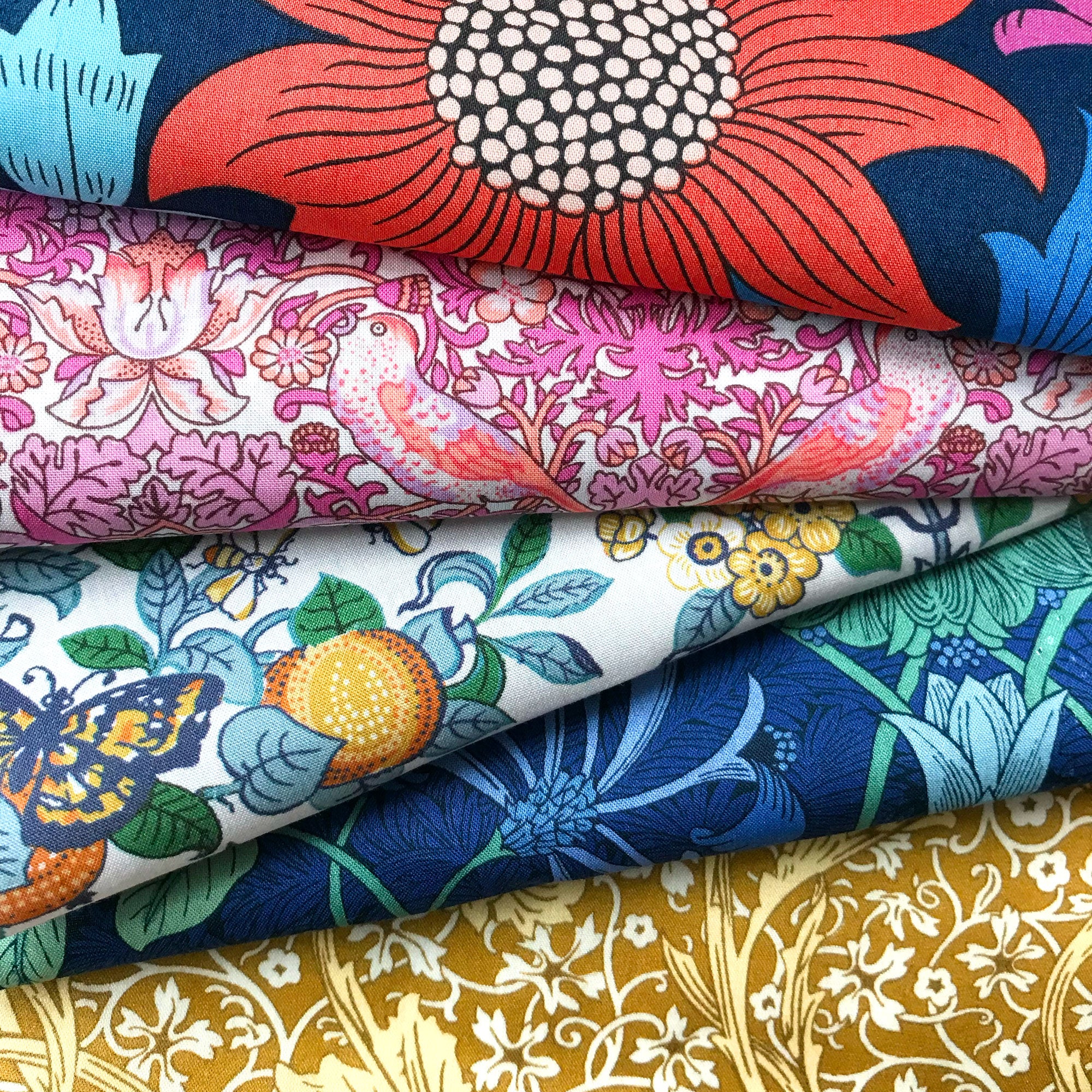 Stack of colorful floral and nature-themed fabrics