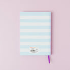 Notebook with pastel blue and white striped cover on a pink background