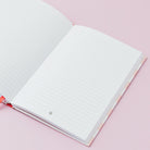Open notebook with lined pages on a pink background