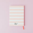 Notebook with pastel striped cover on a pink background