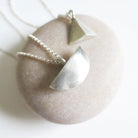 Silver necklace with a geometric pendant on a stone surface