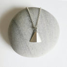 Necklace with a triangular pendant on a stone surface