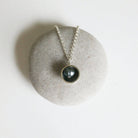 Necklace with a black pendant on a light gray stone surface