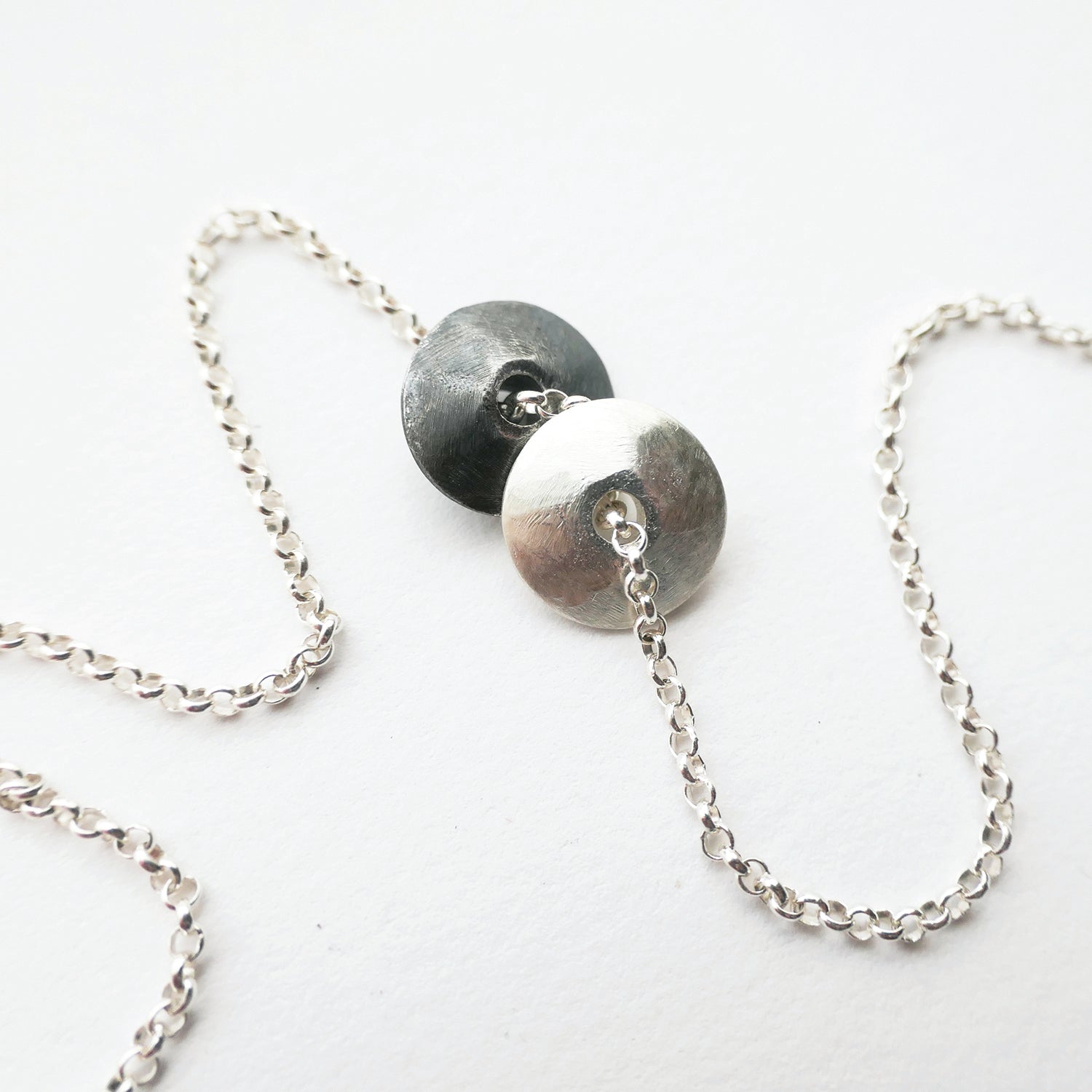Necklace with silver chain and round metal pendants on a white background
