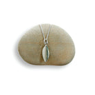 Silver leaf-shaped pendant on a chain, displayed on a green stone.