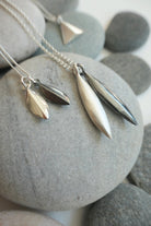Silver seed shaped pendants on a chain against a stone background