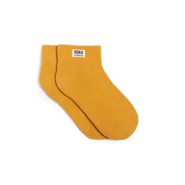 Mustard yellow sock with a Roka label on a white background