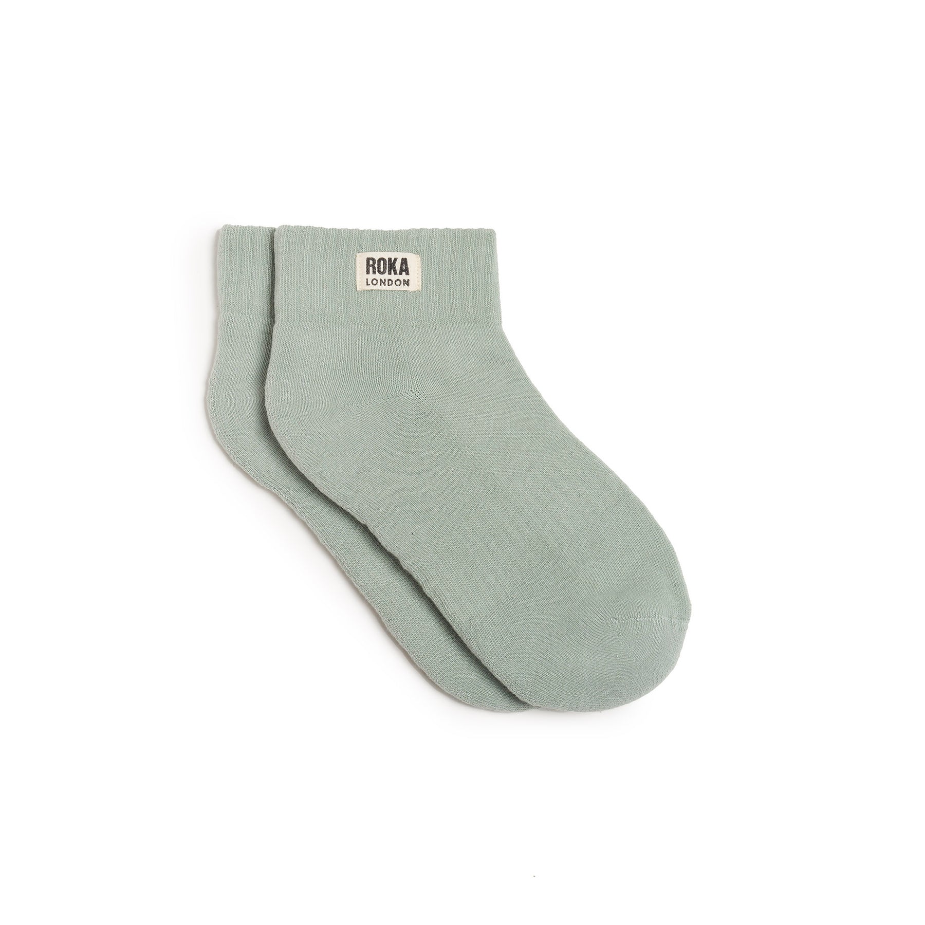 Pair of light green socks with 'ROKA LONDON' label on a white background