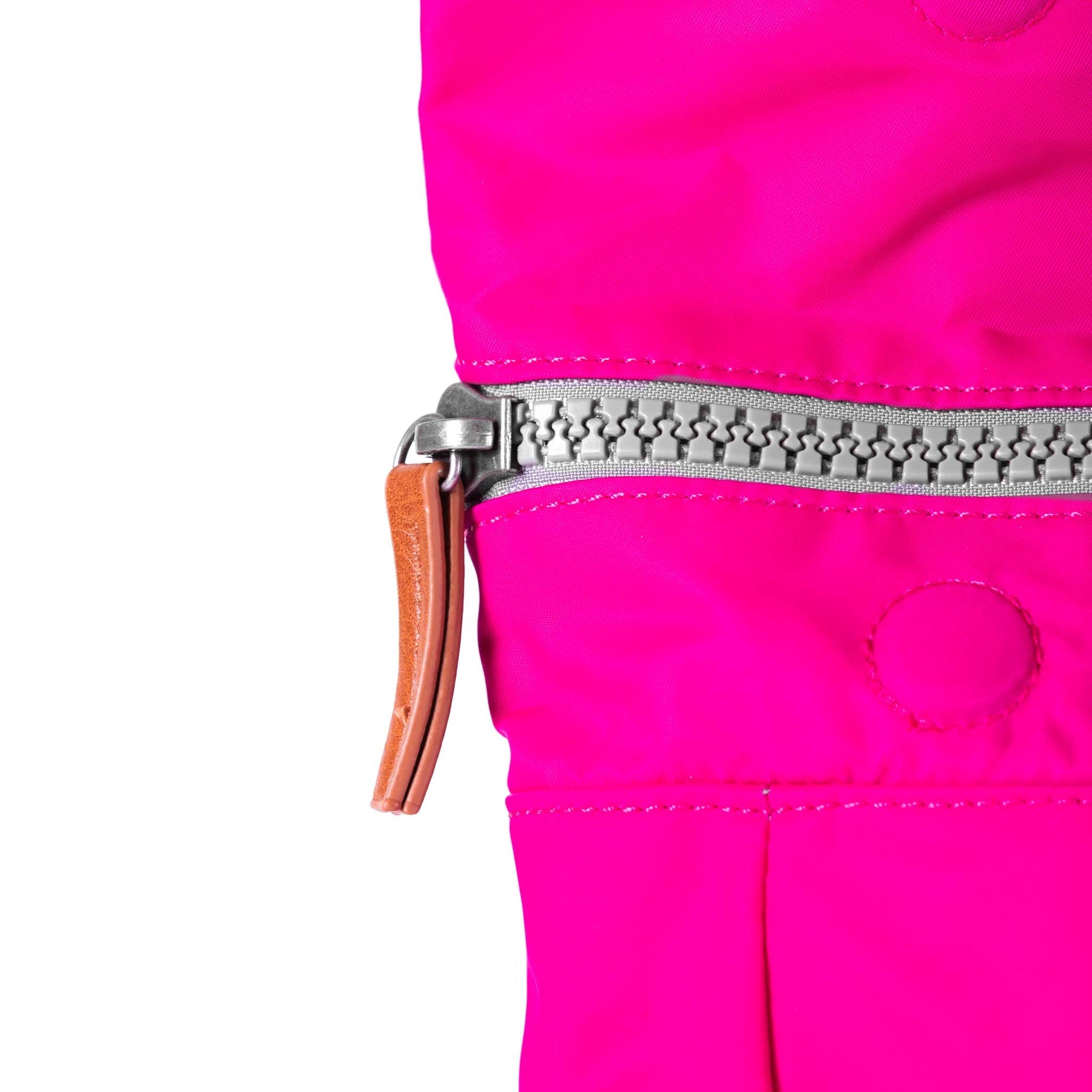Close-up of a pink jacket with a zipper and brown leather pull tab on a white background
