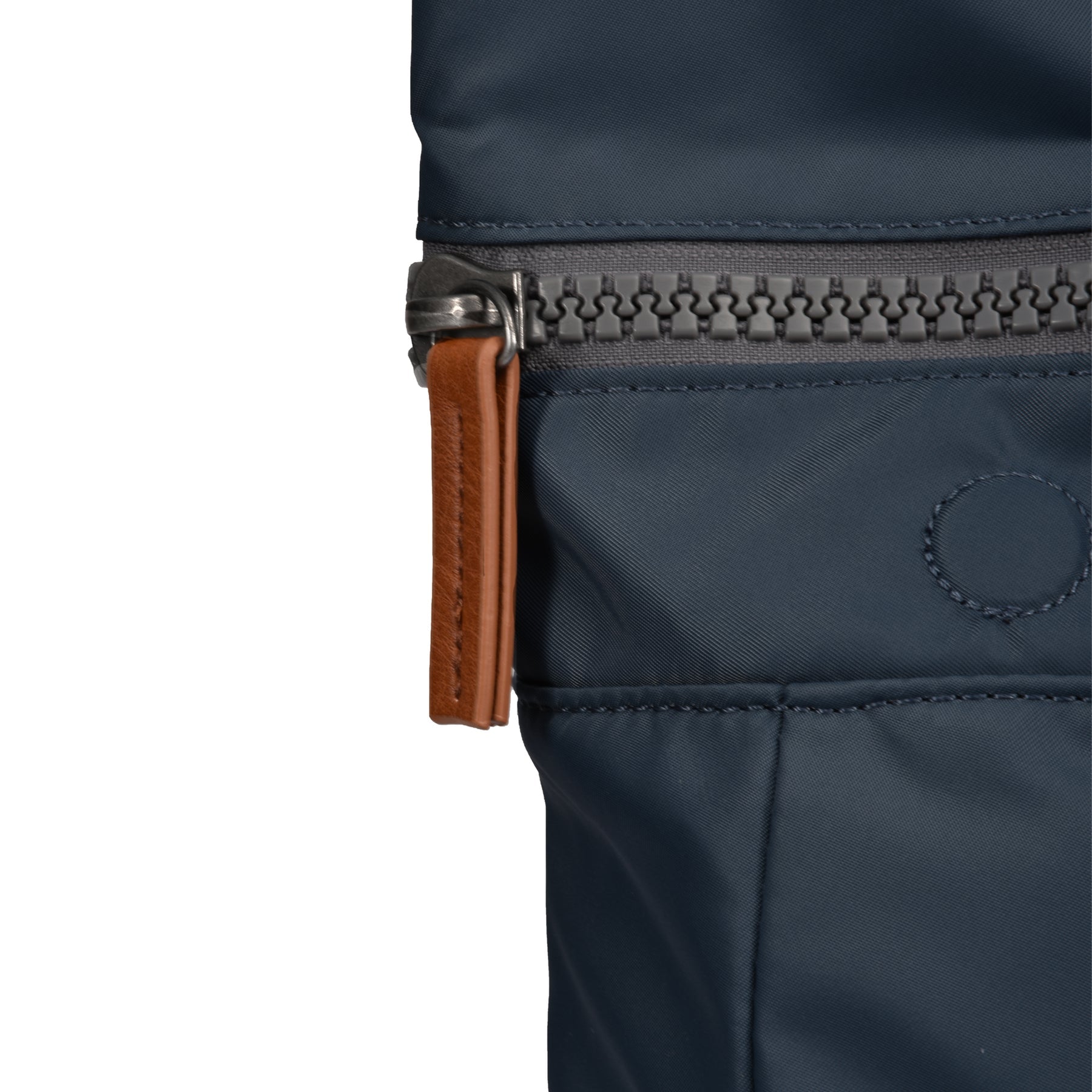 Close-up of a navy blue bag with a brown zipper pull on a white background