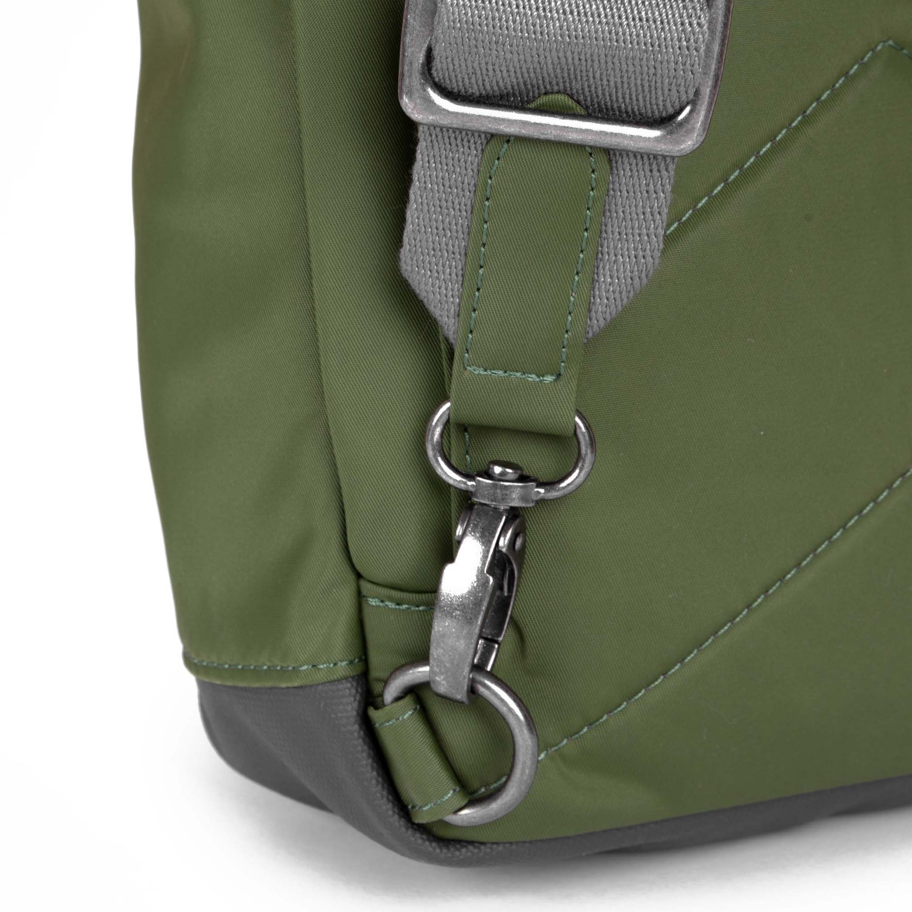 Close-up of a green backpack with a gray strap and metal buckle on a white background