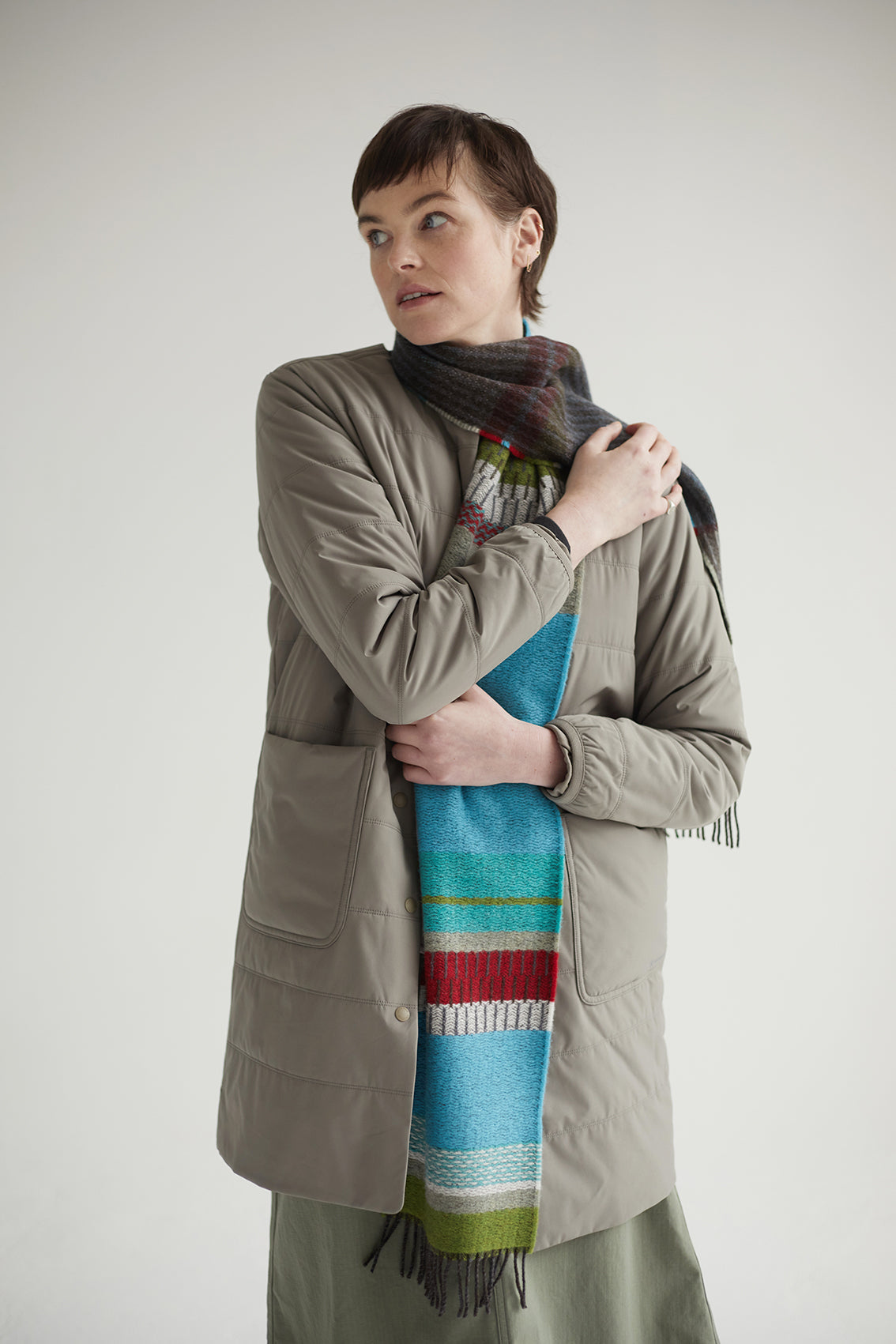 Person wearing a long, colorful scarf with a neutral background