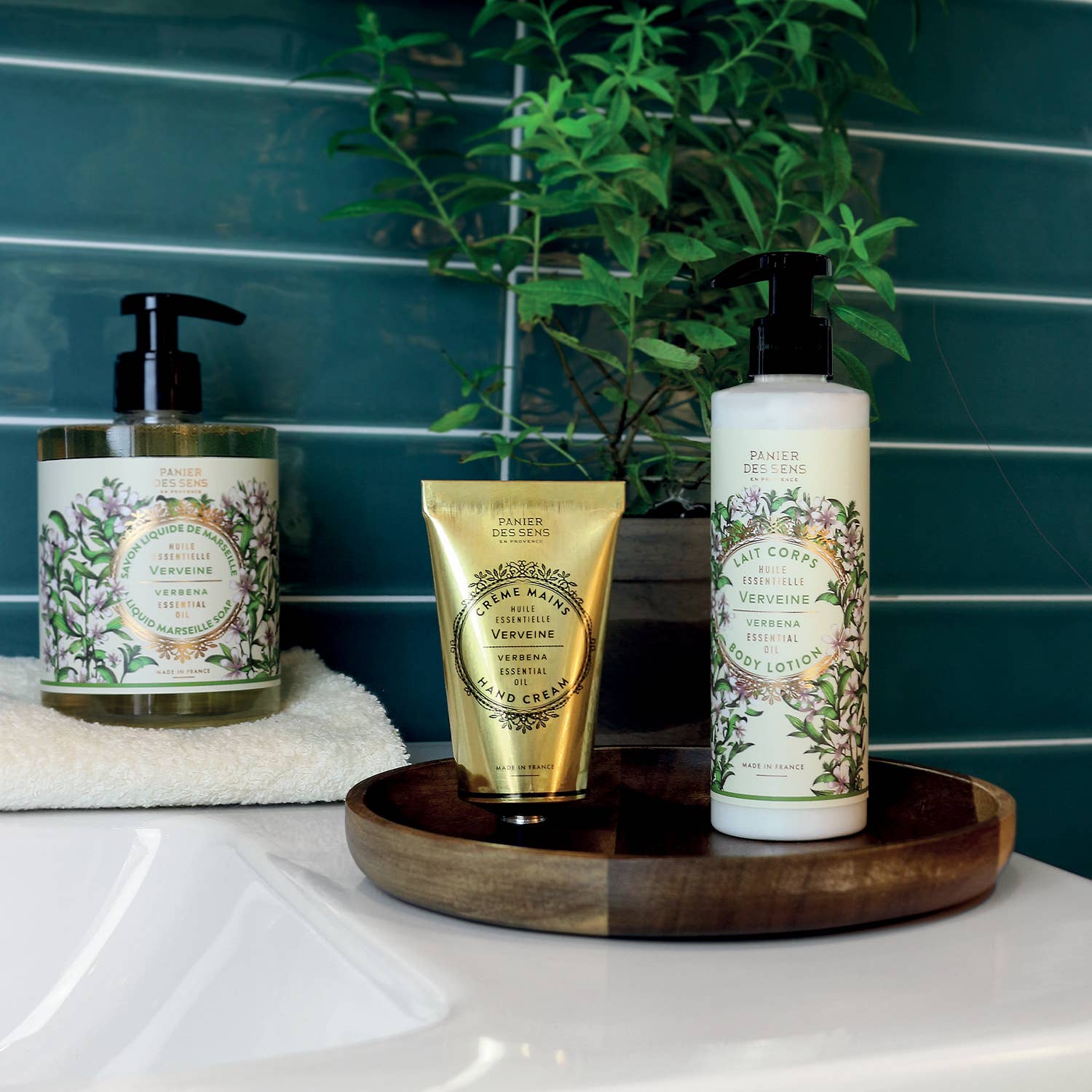 Three skincare products on a wooden tray with a plant in the background.