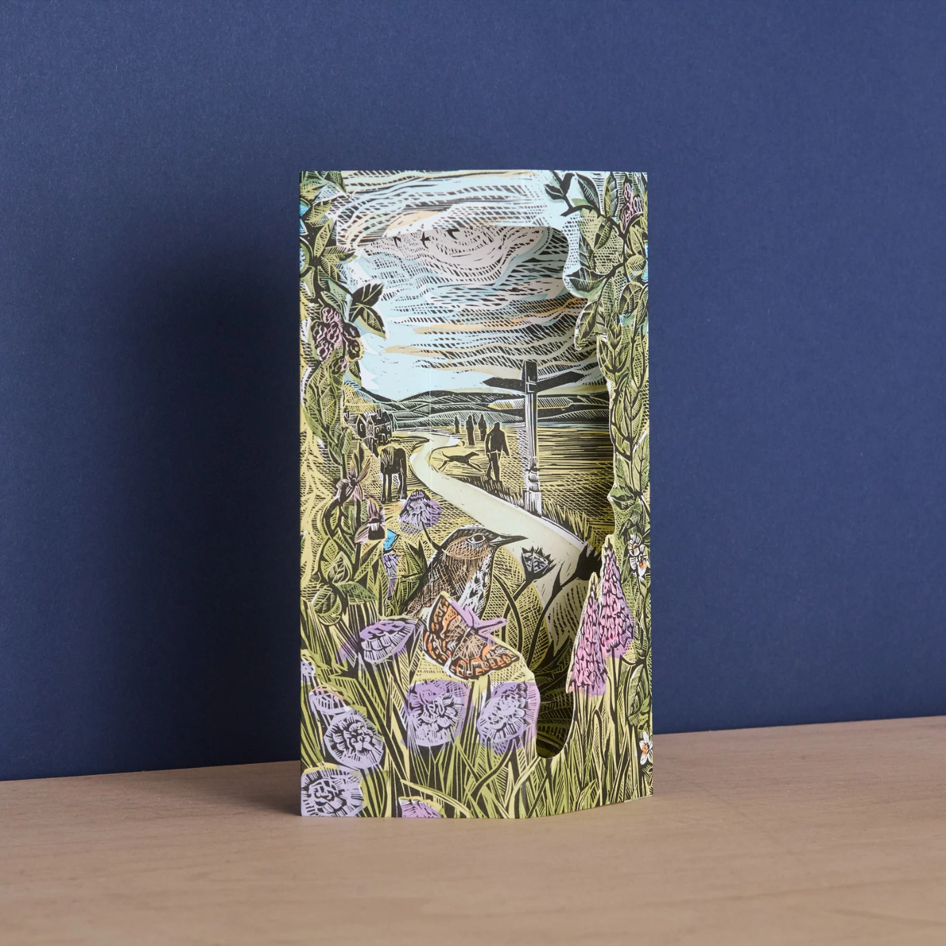 Decorative 3d card with nature-themed design sat on a wooden surface against a blue background