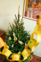 Decorated Christmas tree with ornaments in a room with a framed picture on the wall.
