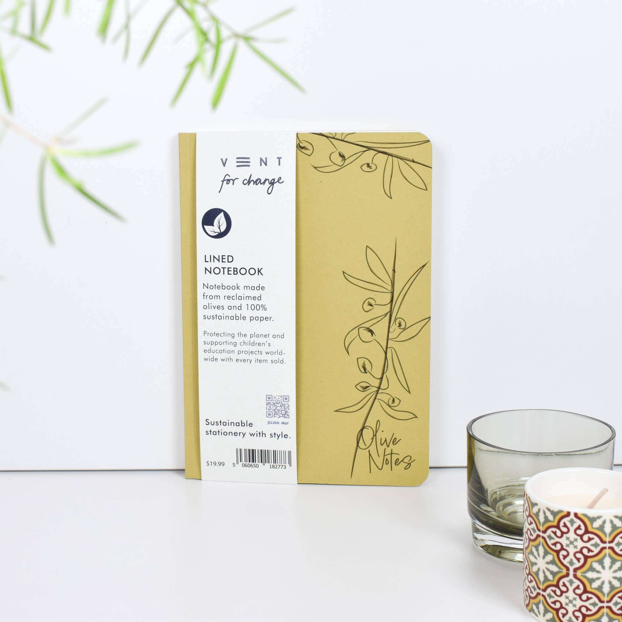 Vent for Change notebook with packaging on a white surface with a glass and candle in the background