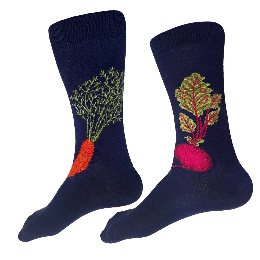 A pair of navy blue crew socks with vegetable designs. One sock features an orange carrot with green leafy stems, and the other features a pinkish-red beet with green and yellow leaves.