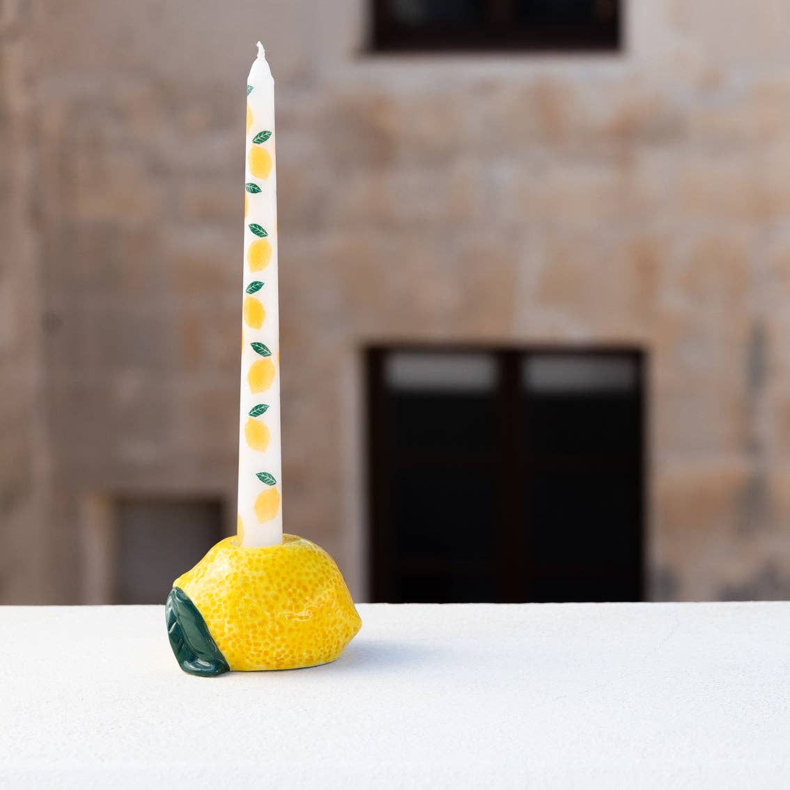 Candle holder shaped like a lemon with a candle on a white surface.