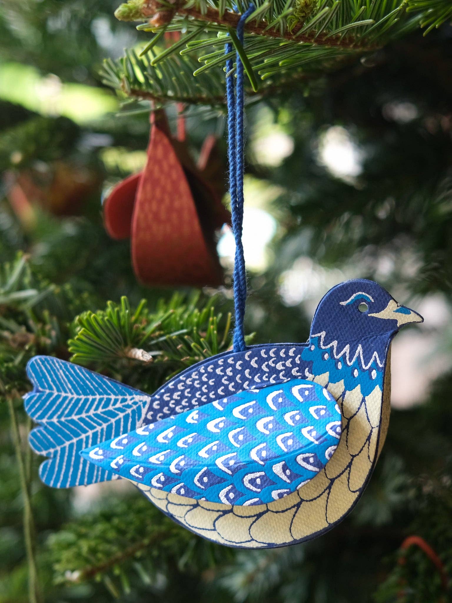 Blue and white bird ornament hanging on a Christmas tree