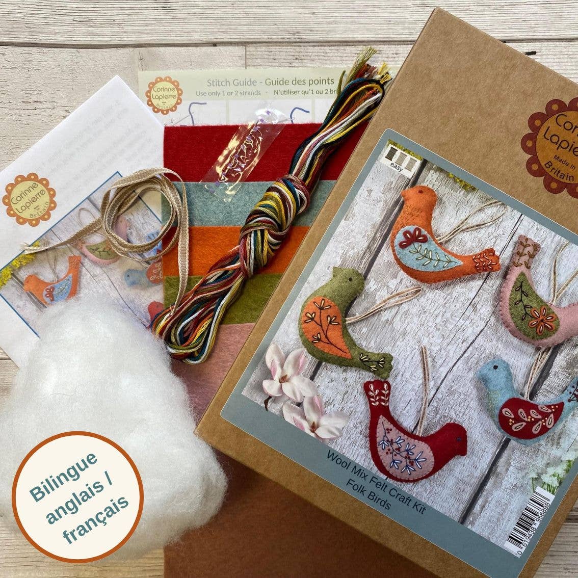 Craft kit with felt birds, thread, and cotton on a wooden surface