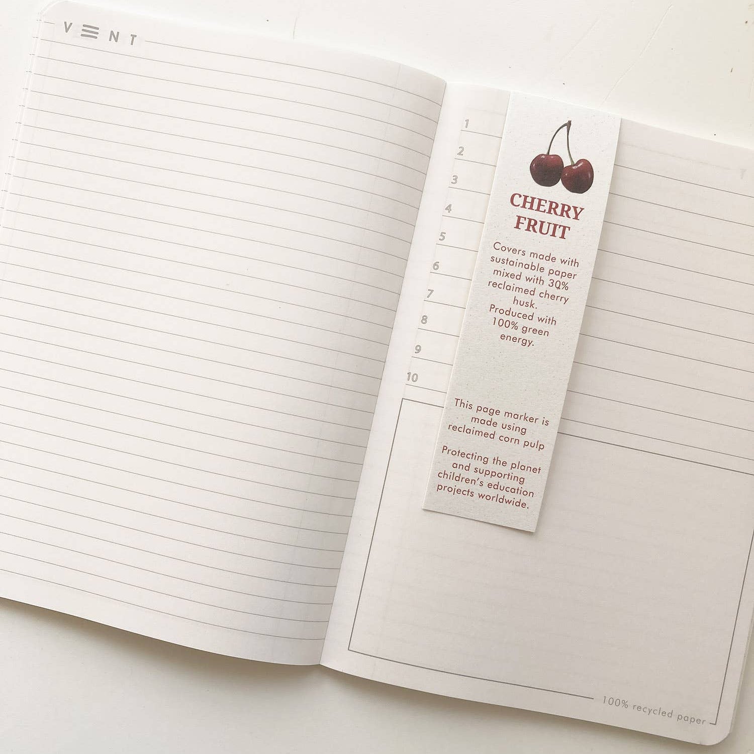 Open notebook with a cherry fruit-themed page marker on a white background