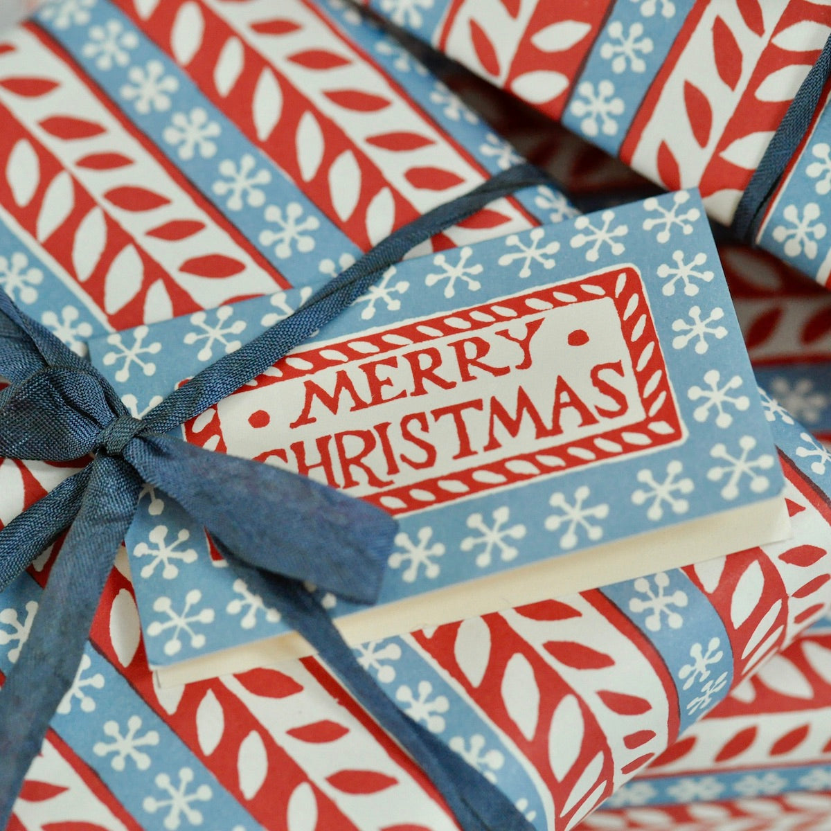 Gift box with red, blue, and white patterned paper and a 'Merry Christmas' tag.